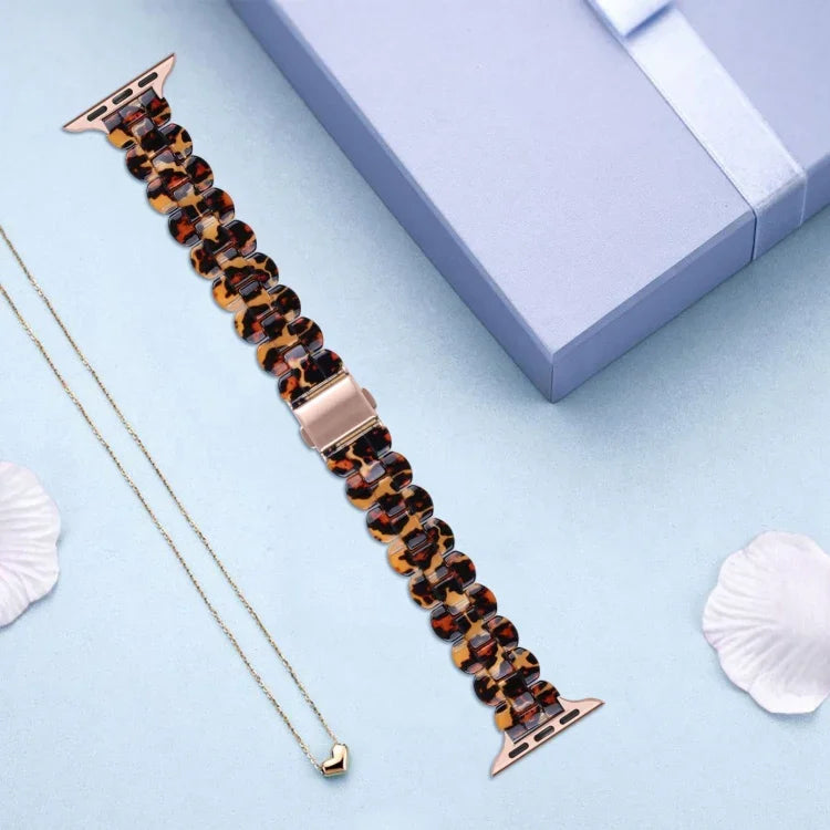 Oval resin replacement strap for Apple Watch displayed next to a gift box and a necklace.