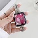Hand holding an Apple Watch with a steel replacement strap for Apple Watch, displaying a colorful watch face, showing time and metrics.